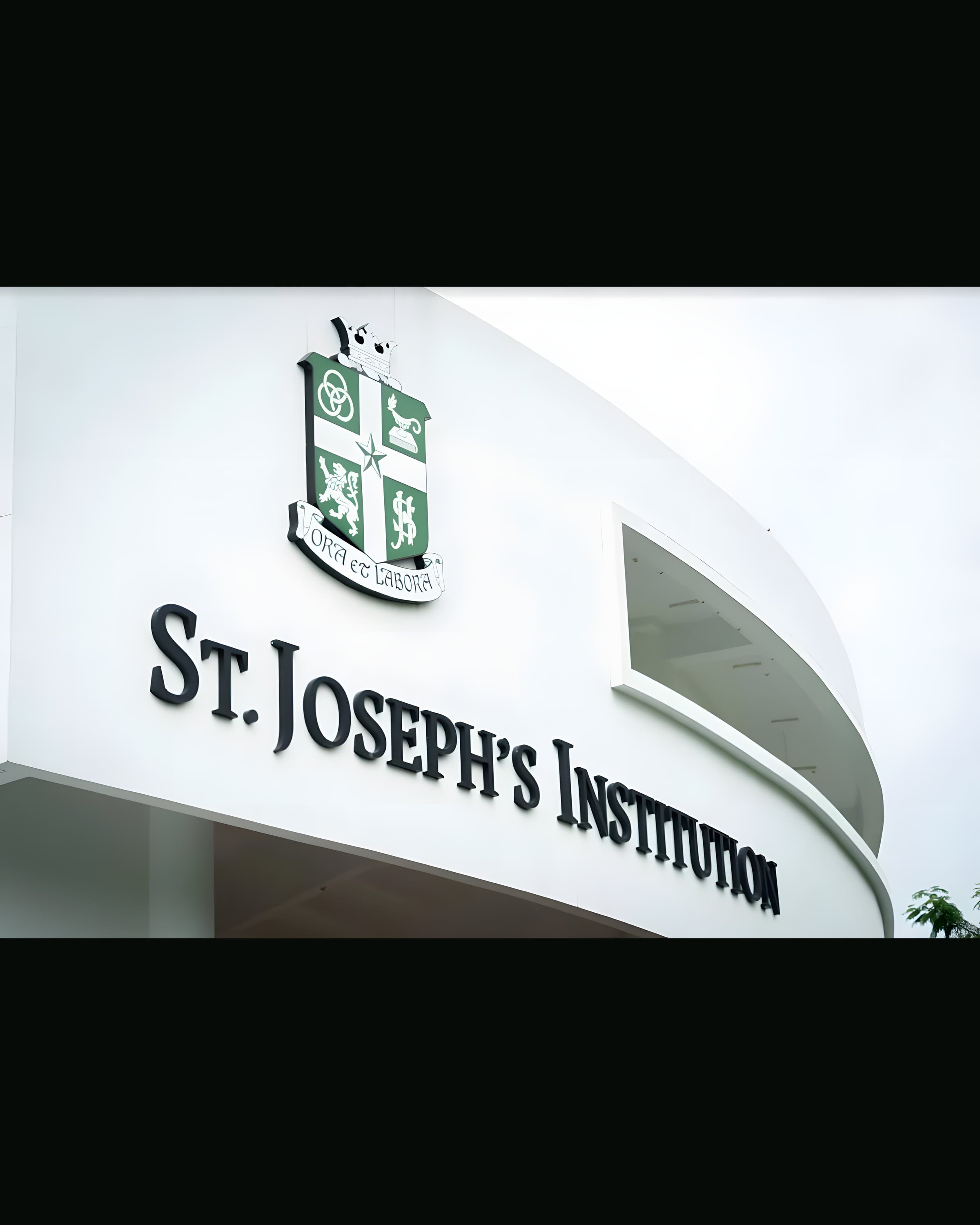 The crest and lettering of St Joseph's Institution on the white curve of its façade.
